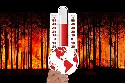 Eine Hand hält eine Erdkugel vor ein Thermometer. Im Hintergrund ein Waldbrand.